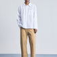 Person wearing a white shirt and beige pants on a plain background
